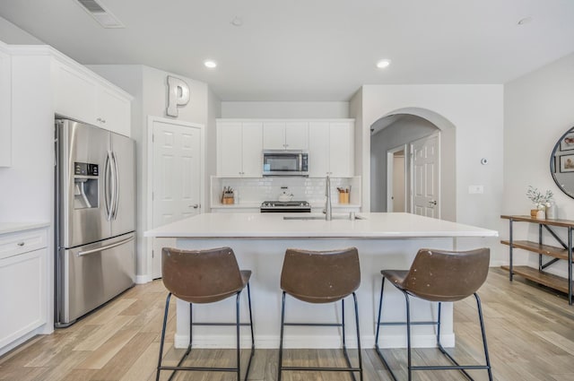 6085 E Homan Ave, Fresno, CA 93727 - kitchen featuring stainless steel appliances, a sink, light wood finished floors, arched walkways, and a breakfast bar area