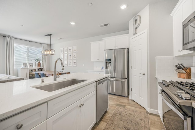6085 E Homan Ave, Fresno, CA 93727 - kitchen with stainless steel appliances, a sink, light wood-type flooring, white cabinetry, and decorative light fixtures