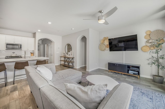 6085 E Homan Ave, Fresno, CA 93727 - living room featuring arched walkways, recessed lighting, light wood-style flooring, ceiling fan, and baseboards