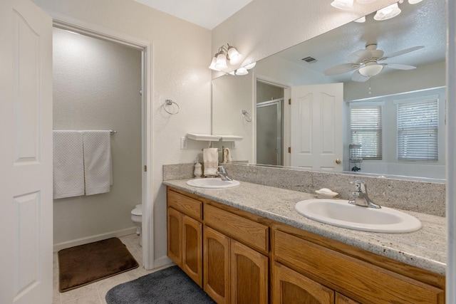 8519 E Olive Ave, Fresno, CA 93737 - bathroom featuring a stall shower, double vanity, toilet, tile patterned flooring, and a ceiling fan