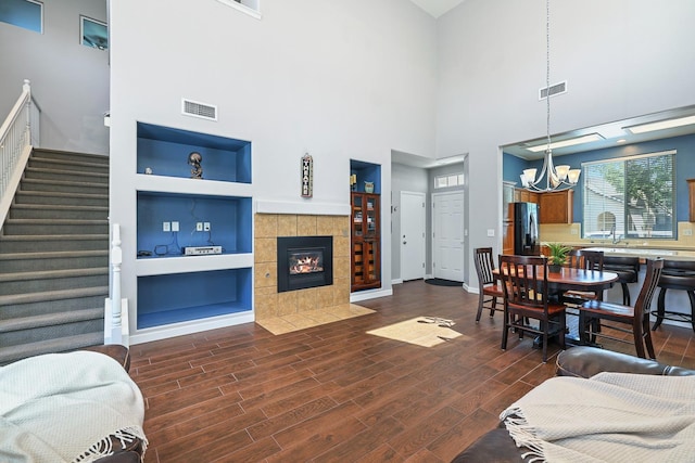73 W Bordeaux Ln, Clovis, CA 93619 - living area with a chandelier, stairs, dark wood-style floors, built in shelves, and a tile fireplace