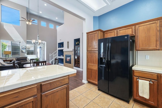 73 W Bordeaux Ln, Clovis, CA 93619 - kitchen with black fridge, a ceiling fan, tile counters, a chandelier, and a high ceiling
