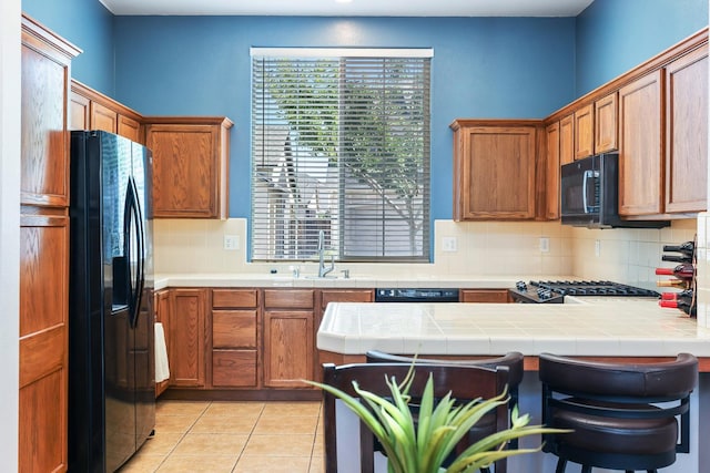 73 W Bordeaux Ln, Clovis, CA 93619 - kitchen with black appliances, a sink, decorative backsplash, a peninsula, and tile counters