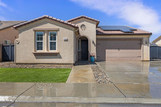 7374 E Flint Way, Fresno, CA 93737 - mediterranean / spanish-style home with an attached garage, stucco siding, roof mounted solar panels, concrete driveway, and a tile roof