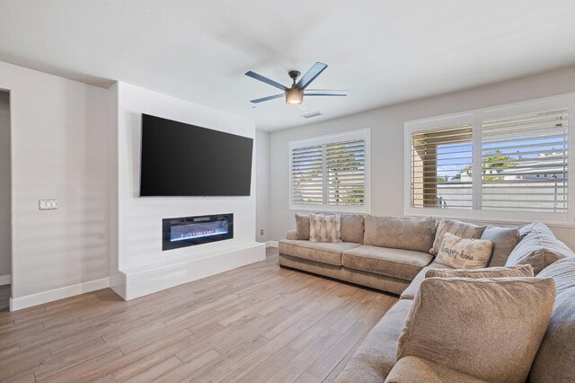 7374 E Flint Way, Fresno, CA 93737 - living area featuring light wood finished floors, a ceiling fan, baseboards, and a glass covered fireplace
