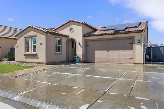 7374 E Flint Way, Fresno, CA 93737 - mediterranean / spanish-style home featuring roof mounted solar panels, an attached garage, concrete driveway, and stucco siding