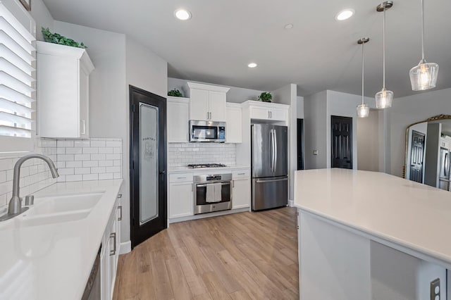 7374 E Flint Way, Fresno, CA 93737 - kitchen featuring appliances with stainless steel finishes, a sink, light wood-style flooring, backsplash, and white cabinetry