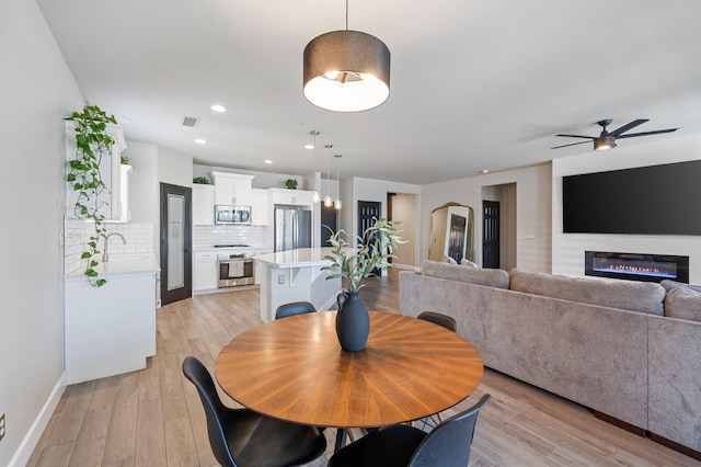 7374 E Flint Way, Fresno, CA 93737 - dining area featuring a ceiling fan, a glass covered fireplace, light wood-type flooring, baseboards, and recessed lighting