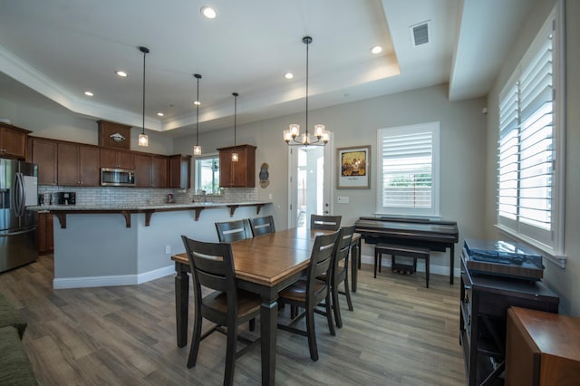 511 Timberline Way S, Madera, CA 93636 - dining space featuring a raised ceiling, wood finished floors, recessed lighting, a chandelier, and healthy amount of natural light
