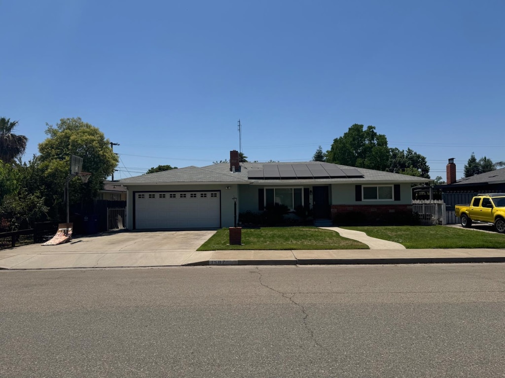 1507 2nd St, Sanger, CA 93657 - ranch-style house with a garage, concrete driveway, and roof mounted solar panels
