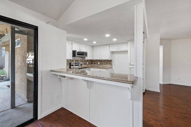6546 N Bendel Ave, Fresno, CA 93722 - kitchen featuring light stone counters, a peninsula, dark wood-style floors, backsplash, and white cabinets