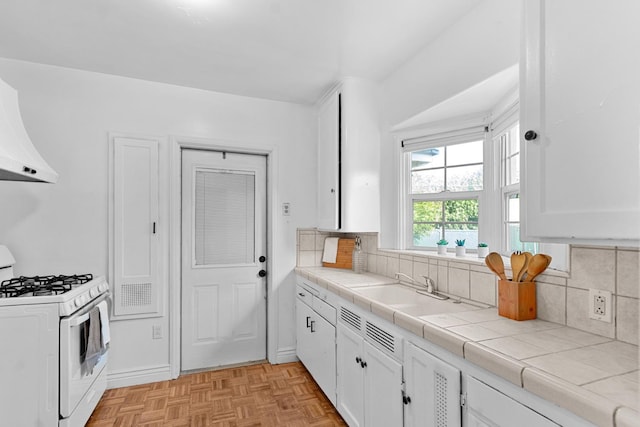 3446 E Lamona Ave, Fresno, CA 93703 - kitchen featuring white range with gas stovetop, tile countertops, white cabinetry, and decorative backsplash