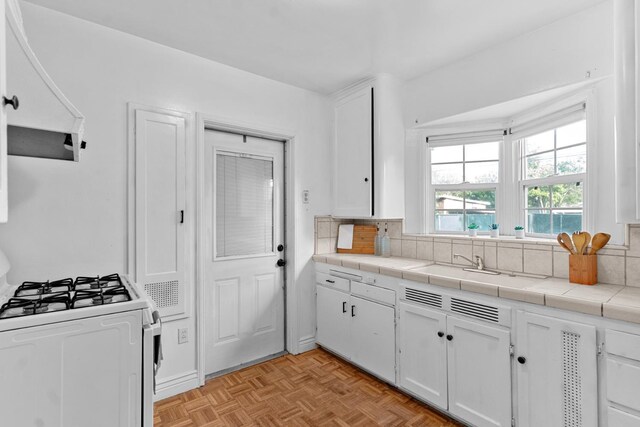 3446 E Lamona Ave, Fresno, CA 93703 - kitchen with white range with gas stovetop, white cabinets, custom exhaust hood, and decorative backsplash