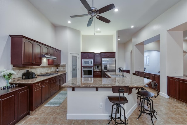 3126 San Gabriel Ave, Clovis, CA 93619 - kitchen with stainless steel appliances, an island with sink, a kitchen breakfast bar, ceiling fan, and decorative backsplash
