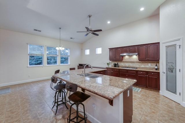 3126 San Gabriel Ave, Clovis, CA 93619 - kitchen featuring a sink, under cabinet range hood, gas cooktop, a breakfast bar, and decorative backsplash