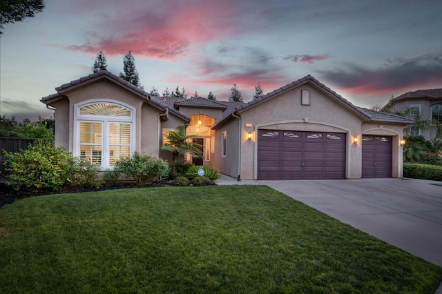3126 San Gabriel Ave, Clovis, CA 93619 - mediterranean / spanish-style house with stucco siding, concrete driveway, an attached garage, a lawn, and a tile roof