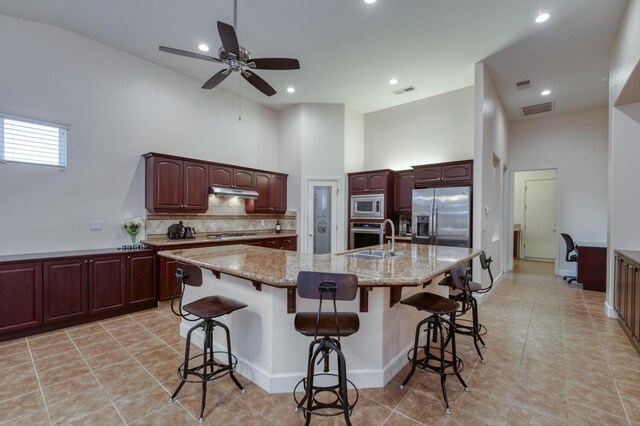 3126 San Gabriel Ave, Clovis, CA 93619 - kitchen featuring appliances with stainless steel finishes, a towering ceiling, tasteful backsplash, a sink, and a breakfast bar