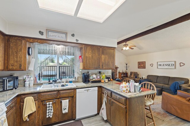 2724 Monocott Dr, Madera, CA 93637 - kitchen with white dishwasher, a sink, a peninsula, open floor plan, and a kitchen bar