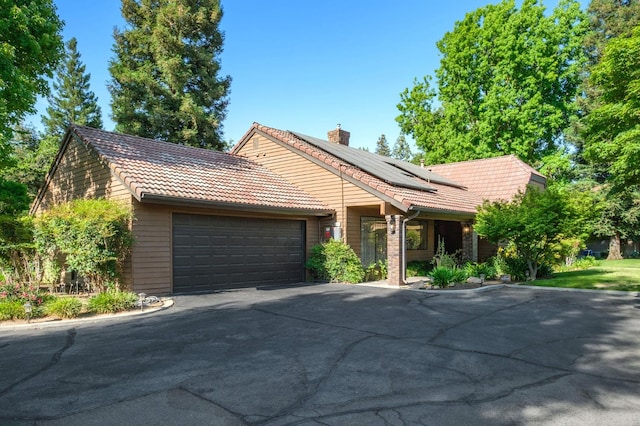 2063 W Barstow Ave, Fresno, CA 93711 - view of front of house with a tile roof, solar panels, an attached garage, a chimney, and driveway