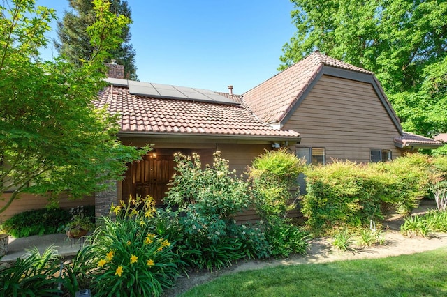 2063 W Barstow Ave, Fresno, CA 93711 - view of home's exterior with solar panels, a chimney, and a tiled roof