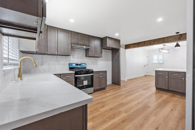 5075 N College Ave, Fresno, CA 93704 - kitchen featuring stainless steel range with gas stovetop, a sink, under cabinet range hood, backsplash, and dark brown cabinets