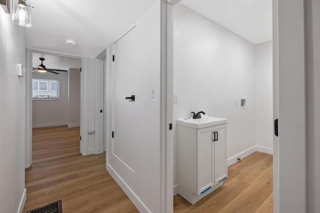 5075 N College Ave, Fresno, CA 93704 - corridor with light wood-style flooring, baseboards, and a sink