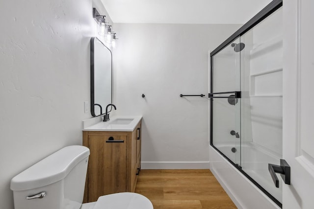 5075 N College Ave, Fresno, CA 93704 - bathroom featuring toilet, vanity, wood finished floors, enclosed tub / shower combo, and baseboards