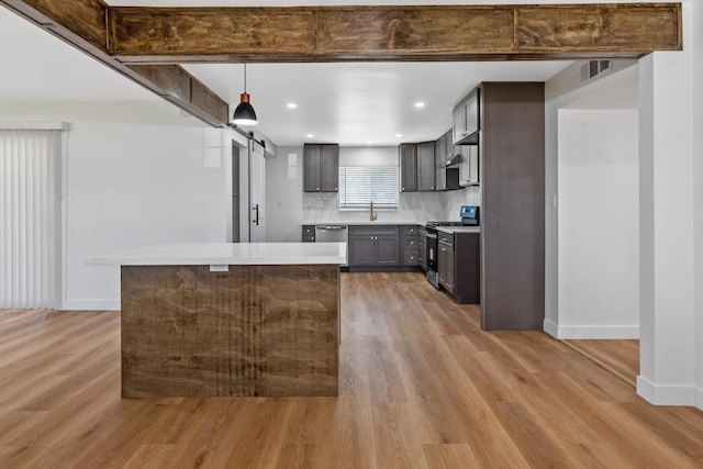 5075 N College Ave, Fresno, CA 93704 - kitchen with stainless steel appliances, light wood finished floors, a barn door, light countertops, and baseboards
