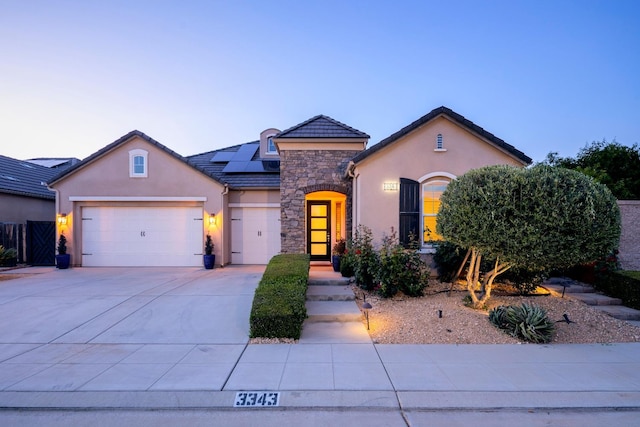 3343 Richmond Ave, Clovis, CA 93619 - french country inspired facade featuring stucco siding, stone siding, roof mounted solar panels, an attached garage, and concrete driveway