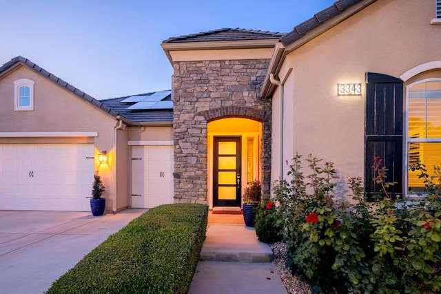3343 Richmond Ave, Clovis, CA 93619 - entrance to property featuring stucco siding, roof mounted solar panels, stone siding, an attached garage, and driveway