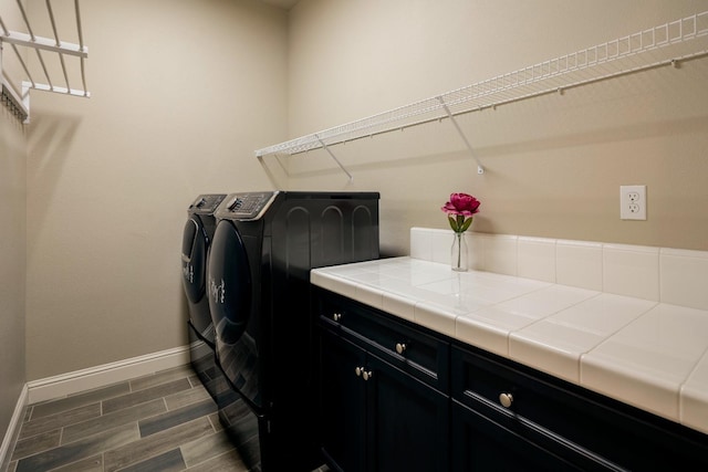 3343 Richmond Ave, Clovis, CA 93619 - washroom with washer and dryer, baseboards, dark wood-type flooring, and cabinet space