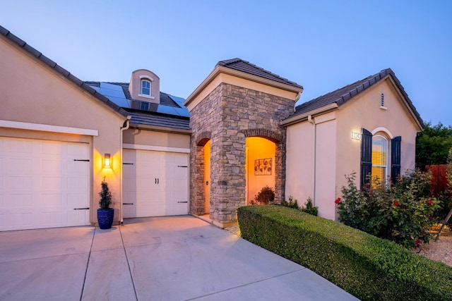 3343 Richmond Ave, Clovis, CA 93619 - view of front of home featuring concrete driveway, roof mounted solar panels, stucco siding, an attached garage, and stone siding