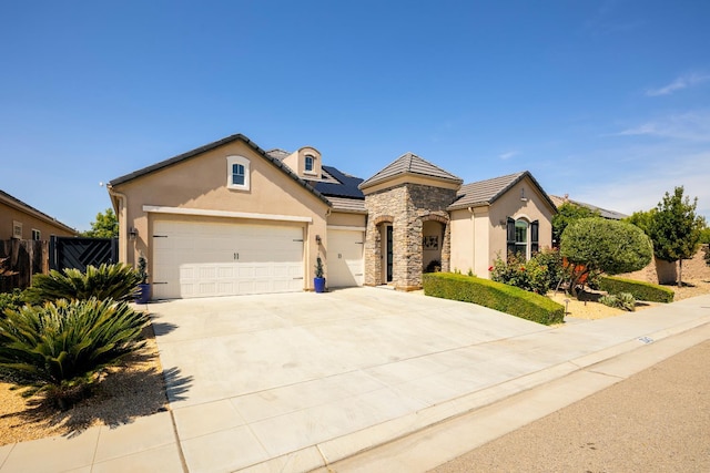 3343 Richmond Ave, Clovis, CA 93619 - view of front of property with stucco siding, a garage, driveway, stone siding, and roof mounted solar panels