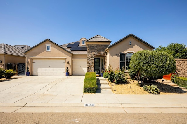 3343 Richmond Ave, Clovis, CA 93619 - view of front of home featuring stucco siding, stone siding, solar panels, an attached garage, and concrete driveway
