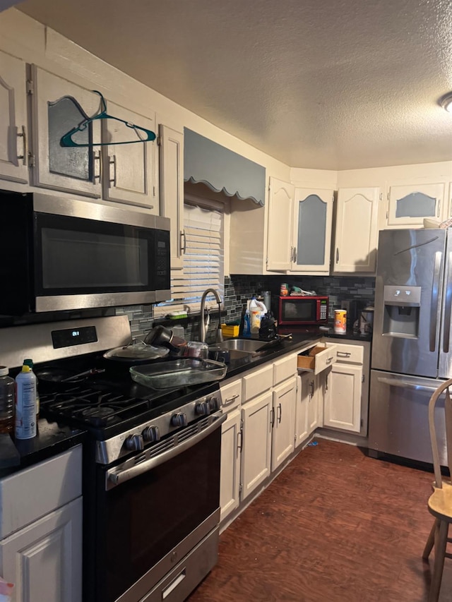 2316 S Eunice Ave, Fresno, CA 93706 - kitchen featuring appliances with stainless steel finishes, a sink, dark countertops, backsplash, and white cabinets