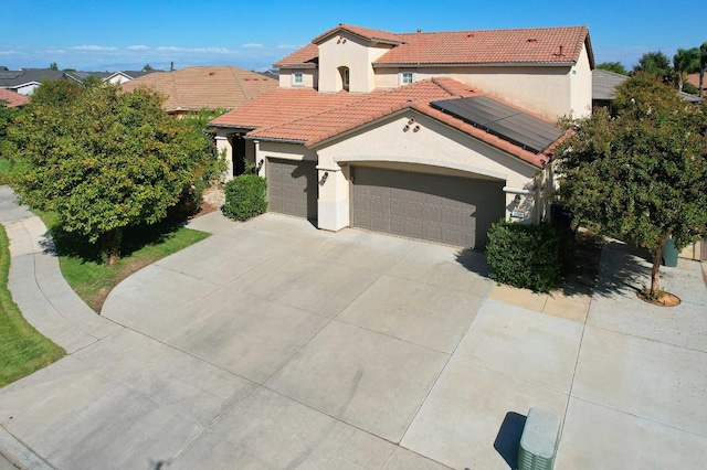 3356 N Burgan Ave, Fresno, CA 93727 - mediterranean / spanish-style house featuring stucco siding, a garage, a tile roof, concrete driveway, and roof mounted solar panels