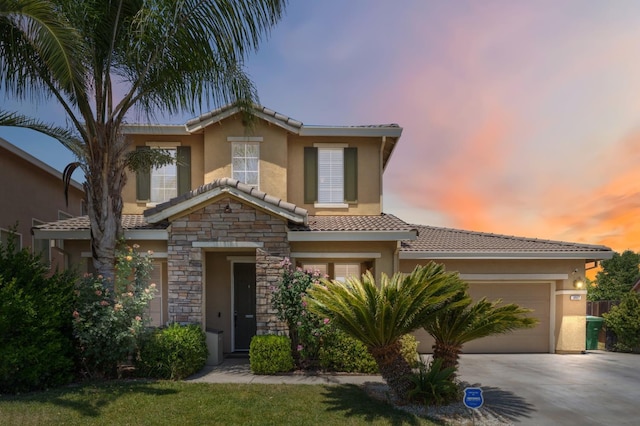 1067 San Diego Ave, Madera, CA 93637 - mediterranean / spanish home featuring stucco siding, a tiled roof, an attached garage, driveway, and stone siding