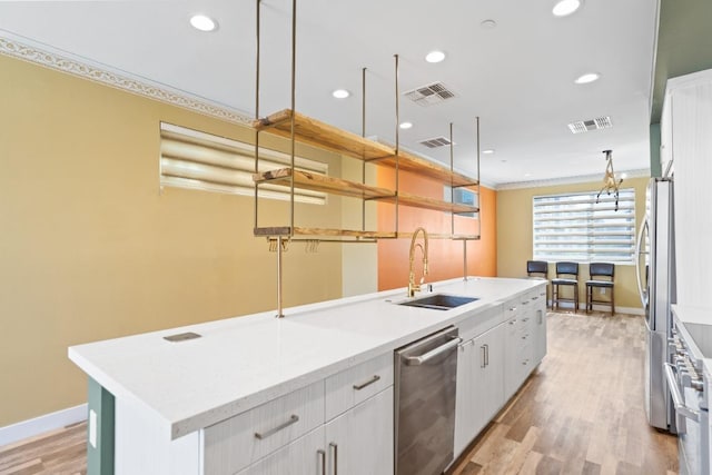 977 24th St, Oakland, CA 94607 - kitchen with a sink, stainless steel appliances, crown molding, white cabinets, and baseboards