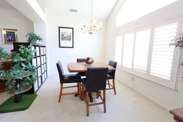 1976 Decatur Ave, Clovis, CA 93611 - dining area with a chandelier, plenty of natural light, light carpet, and vaulted ceiling