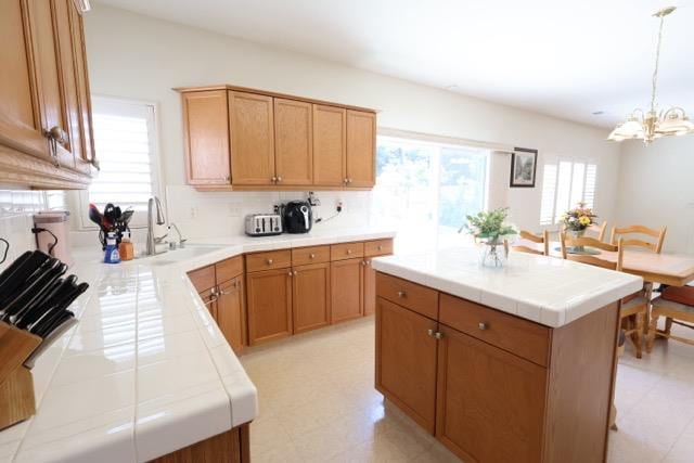 1976 Decatur Ave, Clovis, CA 93611 - kitchen with tile countertops, a chandelier, a sink, hanging light fixtures, and backsplash