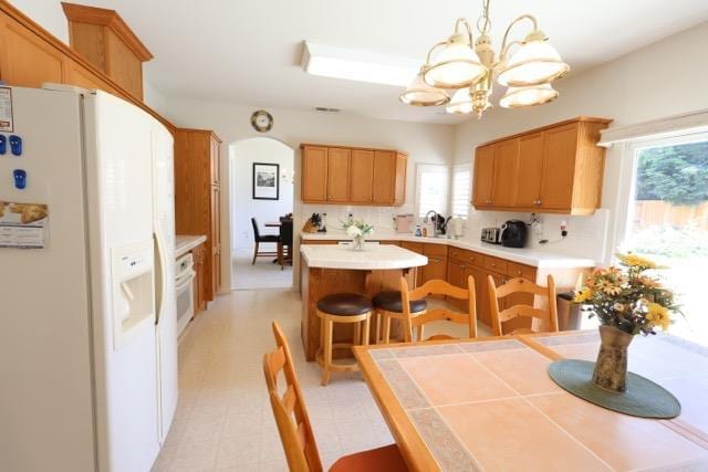 1976 Decatur Ave, Clovis, CA 93611 - kitchen with white refrigerator with ice dispenser, a chandelier, a kitchen island, light countertops, and healthy amount of natural light