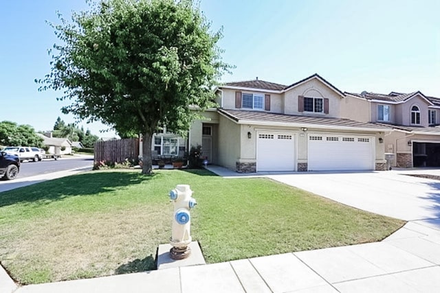 1976 Decatur Ave, Clovis, CA 93611 - view of front of property with stucco siding, concrete driveway, stone siding, a front lawn, and an attached garage