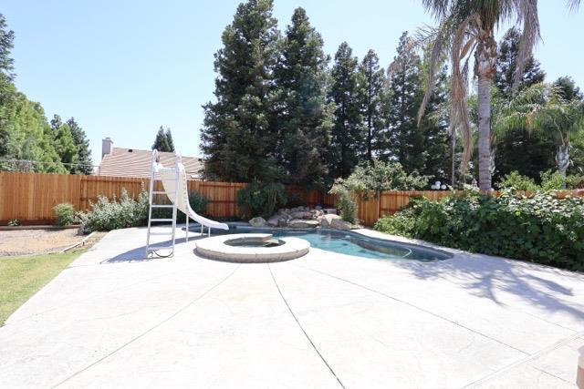 1976 Decatur Ave, Clovis, CA 93611 - view of swimming pool with a water slide, a fenced backyard, a patio area, and a pool with connected hot tub
