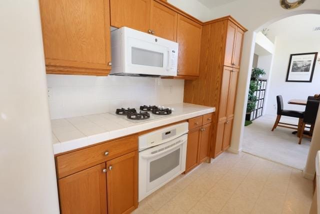 1976 Decatur Ave, Clovis, CA 93611 - kitchen with white appliances, arched walkways, tile counters, backsplash, and brown cabinets