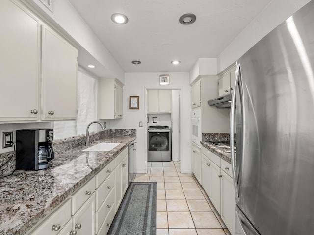 7352 N Adoline Ave, Fresno, CA 93711 - kitchen with appliances with stainless steel finishes, washer / clothes dryer, a sink, under cabinet range hood, and light tile patterned floors