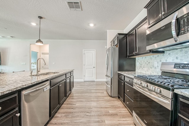 574 Expedition Way, Madera, CA 93636 - kitchen featuring appliances with stainless steel finishes, a sink, light wood-style floors, backsplash, and light stone countertops