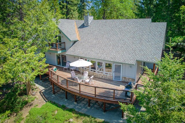 42010 Granite Ledge Ln, Shaver Lake, CA 93664 - back of house with a balcony, a shingled roof, a chimney, a deck, and outdoor dining space