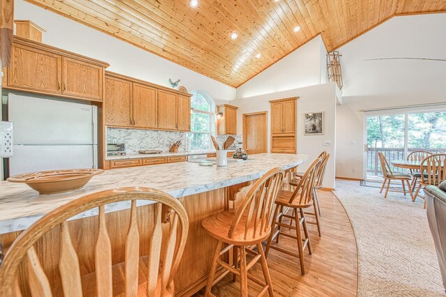 42010 Granite Ledge Ln, Shaver Lake, CA 93664 - kitchen featuring freestanding refrigerator, wood ceiling, a breakfast bar area, high vaulted ceiling, and recessed lighting