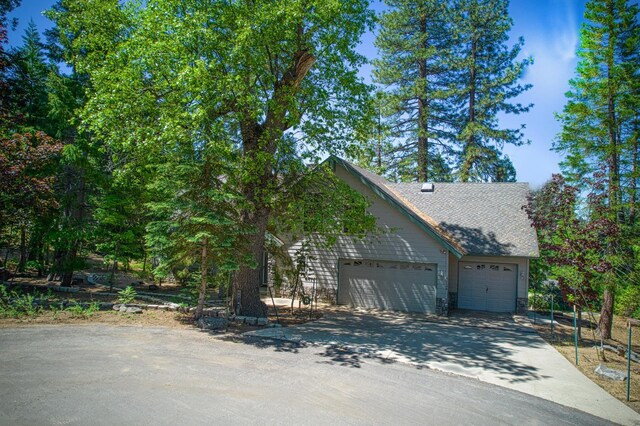 42010 Granite Ledge Ln, Shaver Lake, CA 93664 - view of front of home with driveway, an attached garage, and a shingled roof