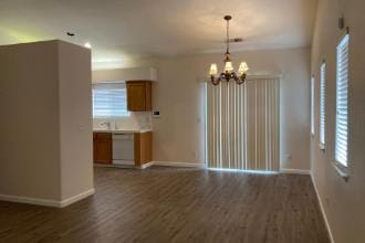 9872 N Woodrow Ave, Fresno, CA 93720 - unfurnished living room featuring a chandelier, baseboards, and dark wood-style floors